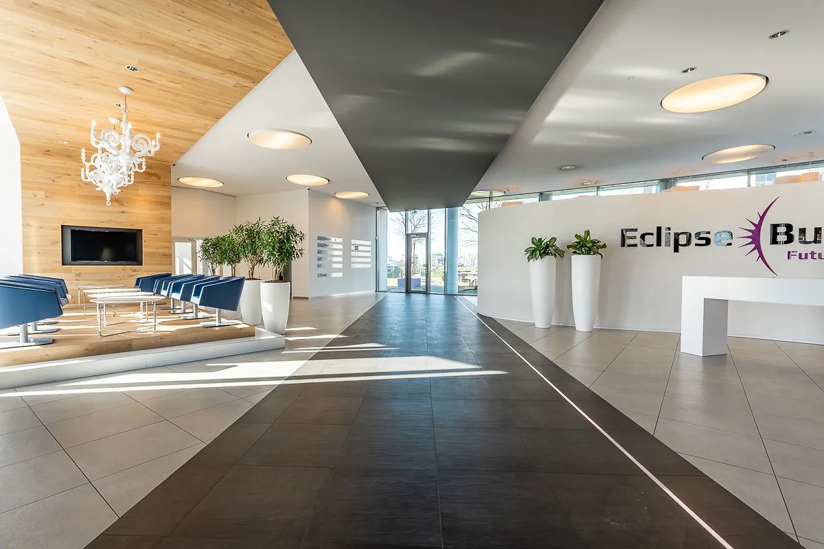 Moderne en lichte ontvangsthal van het kantoorgebouw Rivium Quadrant met zitgedeelte, planten en het logo van Eclipse Business.